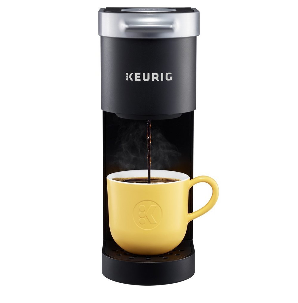 Keurig K-Mini single-serve coffee maker in black with a silver lid, brewing into a yellow mug